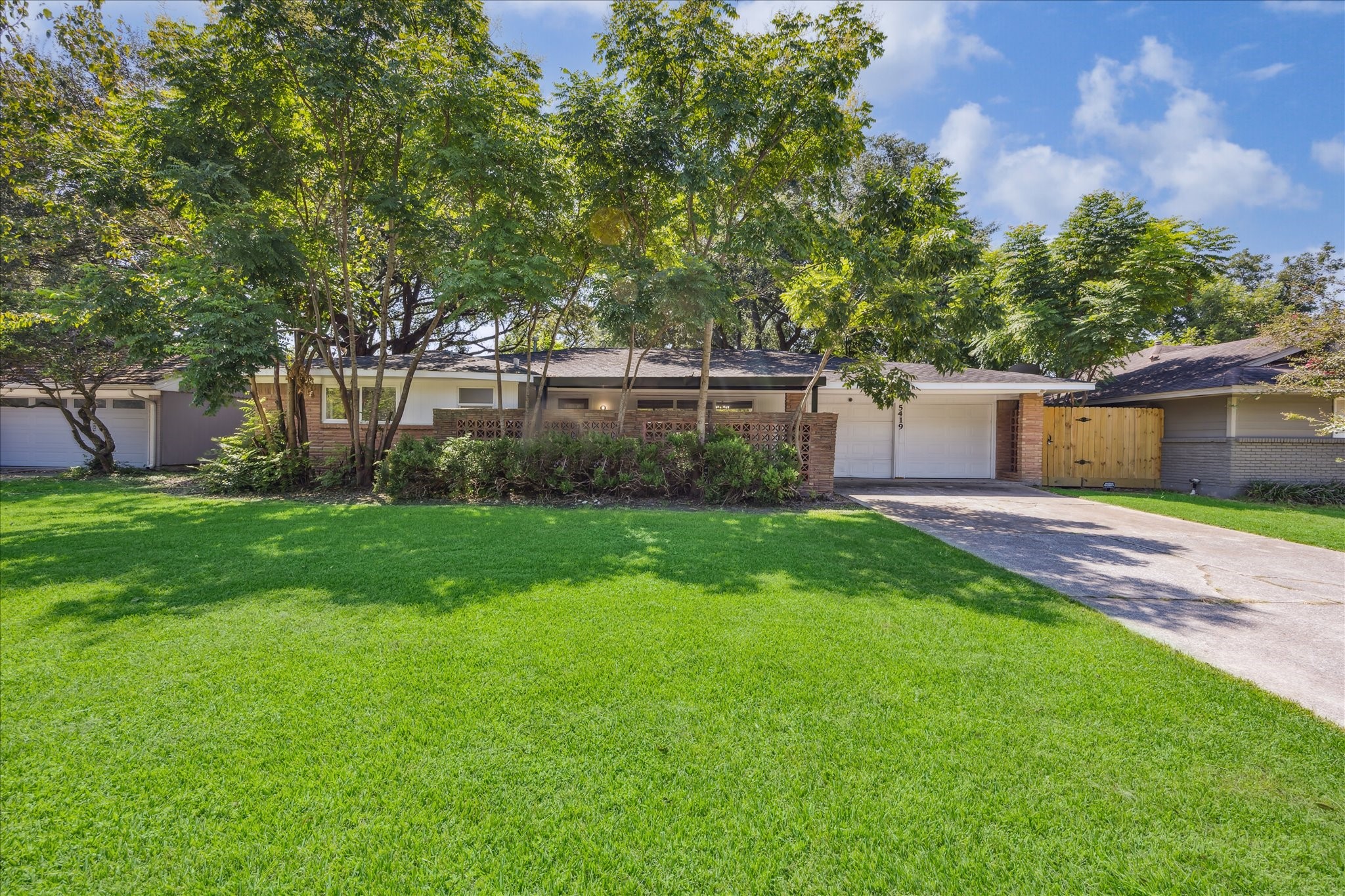 5419 Beechnut Street Houston, TX 77096 - Photo 2 of 28 The front of the home features a shaded front yard with mature trees, brick-accented patio, and a two-car garage.