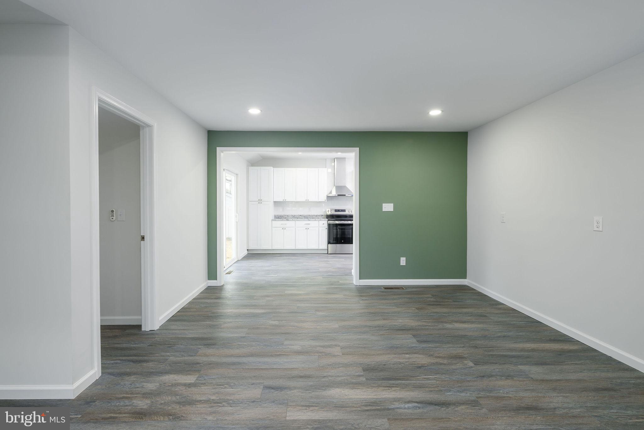 16853 Sherbrooke Road Lewes, DE 19958 - Photo 11 of 32 a view of an empty room with wooden floor and a kitchen