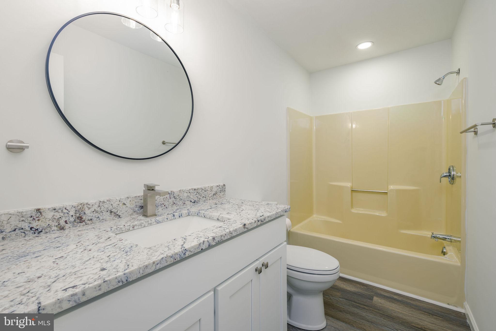 16853 Sherbrooke Road Lewes, DE 19958 - Photo 21 of 32 a bathroom with a granite countertop toilet a sink and a mirror