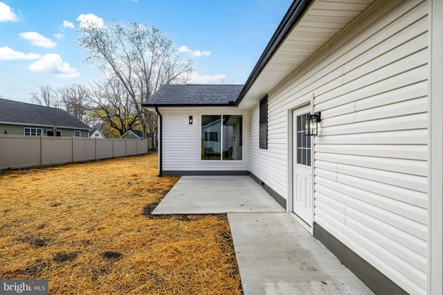an empty room with wooden floor a ceiling fan and a kitchen