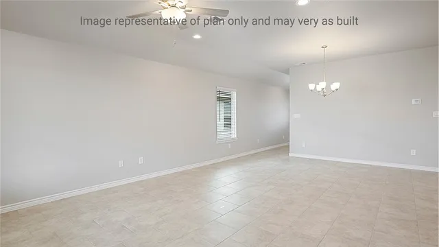 an empty room with a chandelier fan and windows