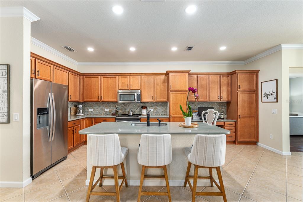 9595 Southwest 70th Loop Ocala, FL 34481 - Photo 34 of 100 a kitchen with stainless steel appliances granite countertop a sink a stove a refrigerator cabinets and a dining table with wooden floor