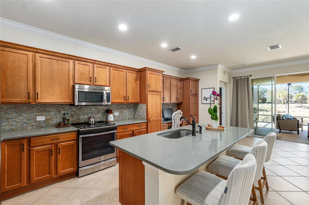 9595 Southwest 70th Loop Ocala, FL 34481 - Photo 37 of 100 a kitchen with stainless steel appliances granite countertop a stove a refrigerator a sink dishwasher a dining table and chairs with wooden floor