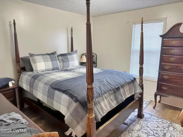 a bedroom with a bed a table and wooden floor