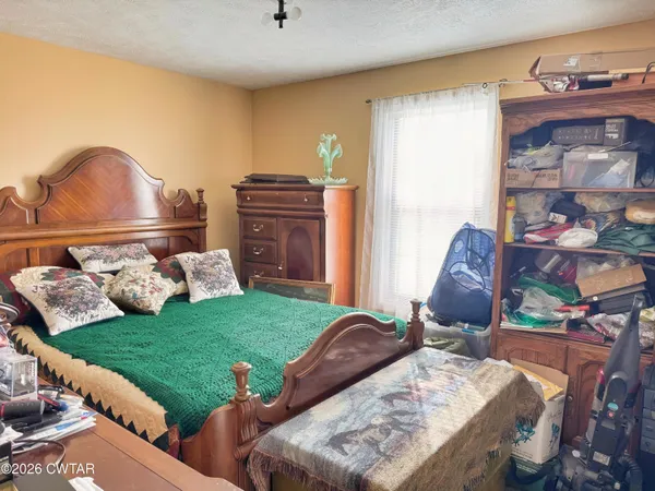 a bed sitting in a room next to a window with lawn chairs and a wooden floor