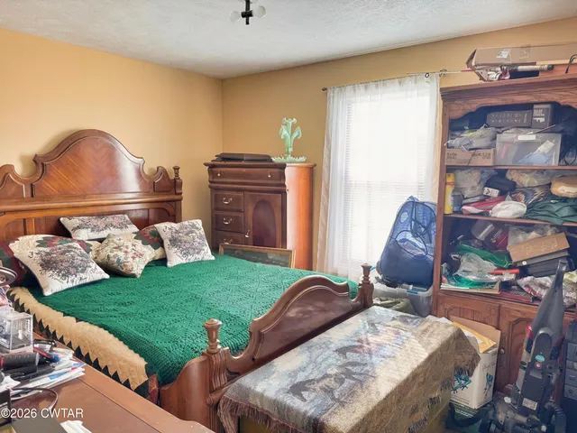 a bed sitting in a room next to a window with lawn chairs and a wooden floor