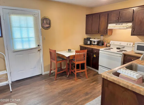 a kitchen with stainless steel appliances granite countertop a table chairs sink and cabinets