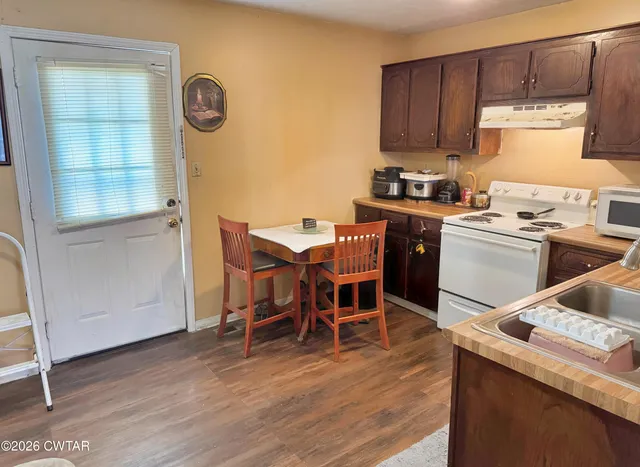 a kitchen with stainless steel appliances granite countertop a table chairs sink and cabinets