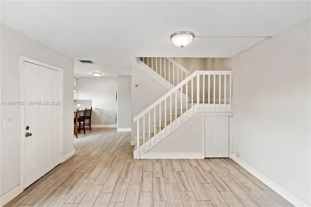 a view of a hallway with wooden floor and stairs