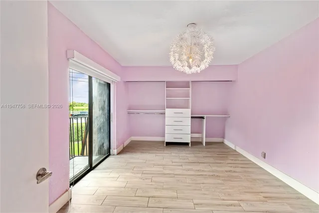an empty room with wooden floor chandelier and windows