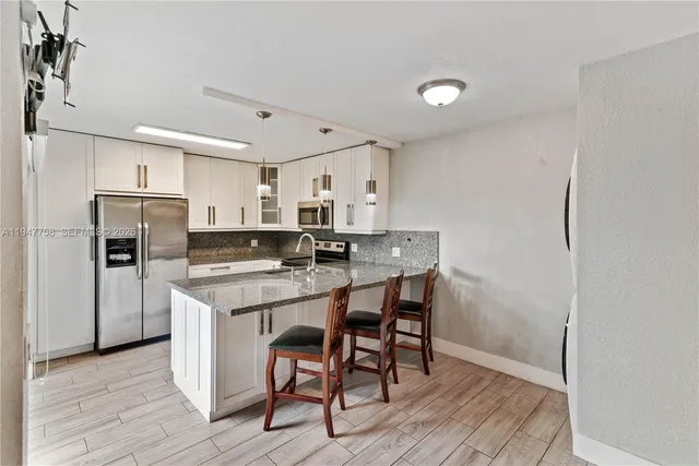 a kitchen with stainless steel appliances a dining table chairs refrigerator sink and cabinets