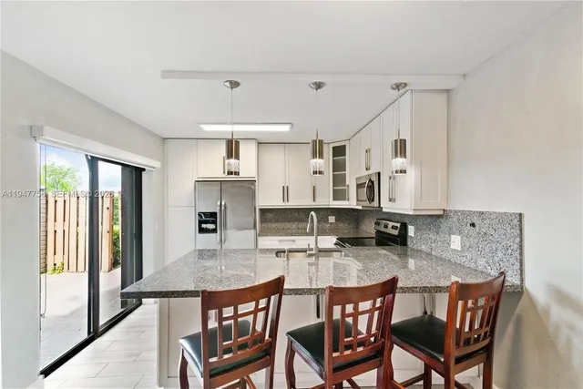 a kitchen with granite countertop a stove a sink a dining table and chairs
