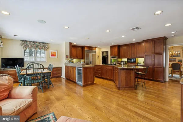 a kitchen with stainless steel appliances kitchen island granite countertop a table chairs sink and cabinets