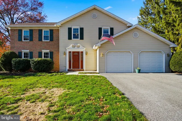 a view of a white house next to a yard with large trees