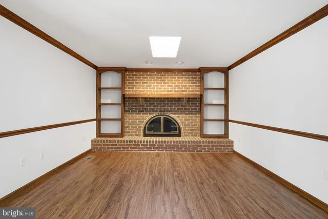 a view of wooden floor a fireplace and windows in an empty room