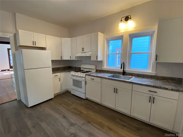 a kitchen with granite countertop white cabinets and white appliances