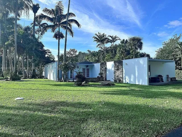 a backyard of a house with table and chairs plants and large tree