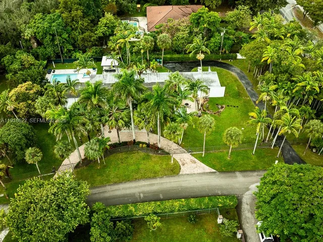 an aerial view of residential house with green space and mountain view in back