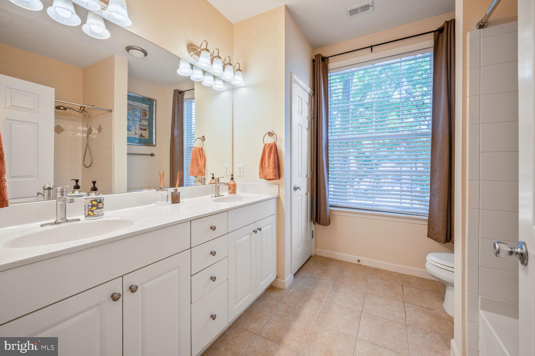 7 Booth Street, Unit 202 Gaithersburg, MD 20878 - Photo 16 of 32 a spacious bathroom with a double vanity sink a large mirror a bathtub and next to a window