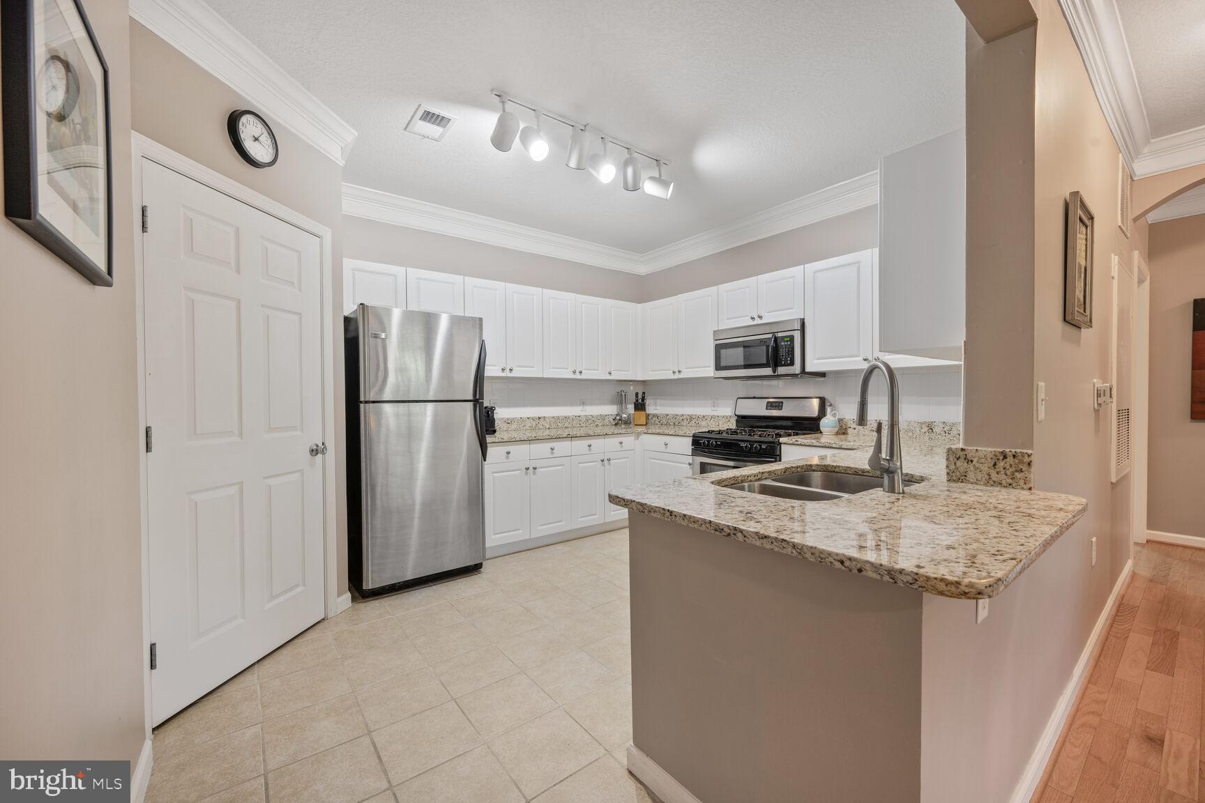 7 Booth Street, Unit 202 Gaithersburg, MD 20878 - Photo 6 of 32 a kitchen with stainless steel appliances granite countertop a refrigerator stove microwave and sink