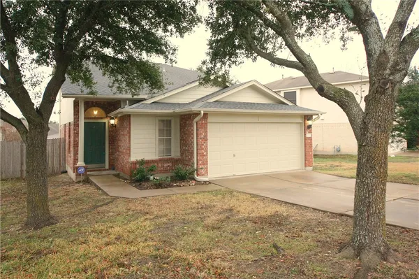 a front view of a house with a yard and large tree