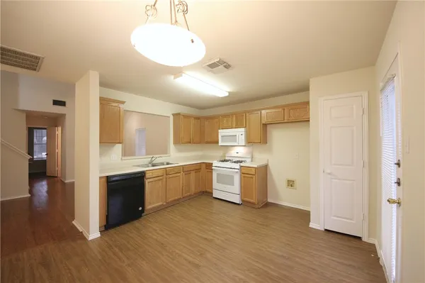 a kitchen with stainless steel appliances granite countertop a stove a sink dishwasher and a refrigerator with wooden floor