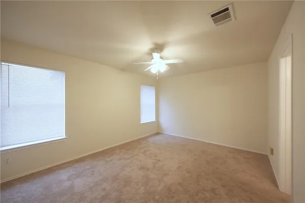 an empty room with a chandelier fan and windows