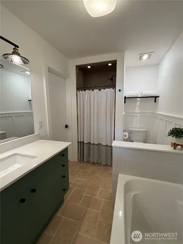 a bathroom with a tub a sink and mirror