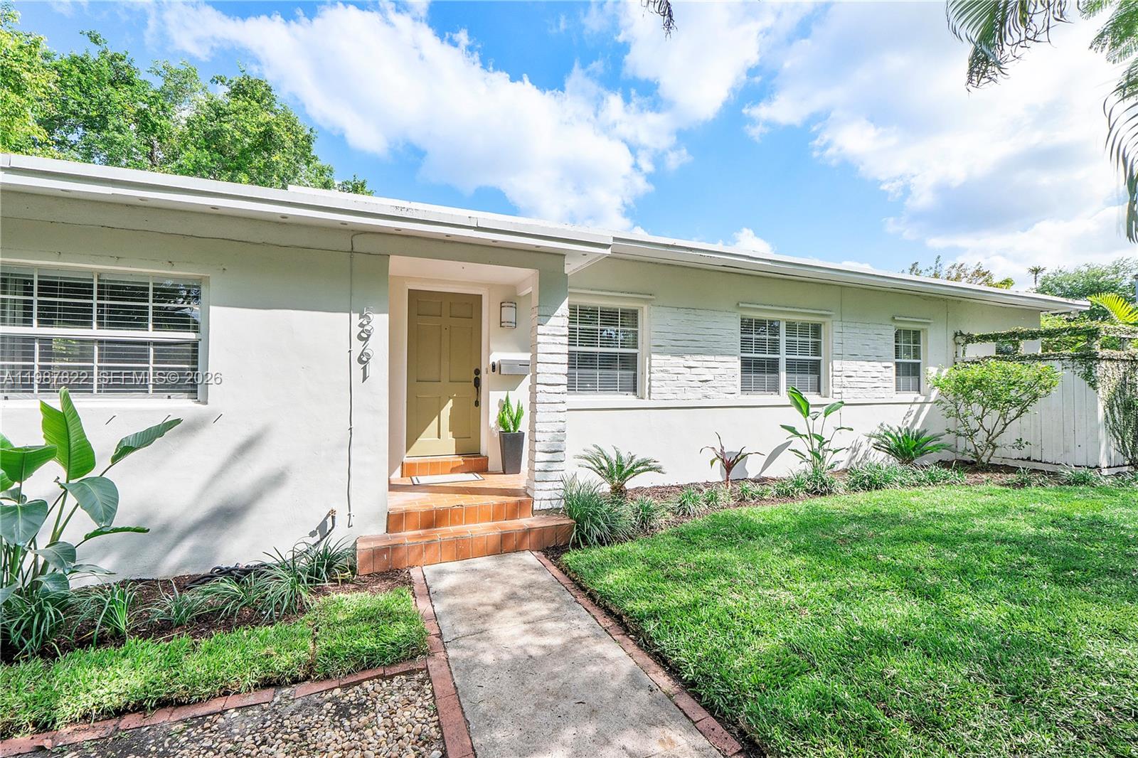 5961 Southwest 46th Terrace Miami, FL 33155 - Photo 2 of 28 a front view of a house with a yard and potted plants
