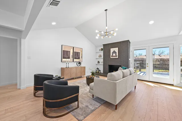 a living room with furniture a chandelier and wooden floor