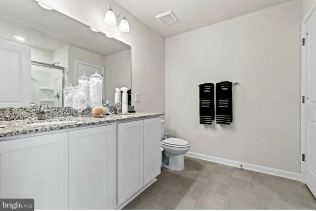 a bathroom with a granite countertop sink mirror vanity and toilet