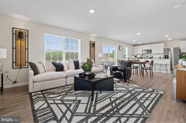 a living room with furniture kitchen view and a large window