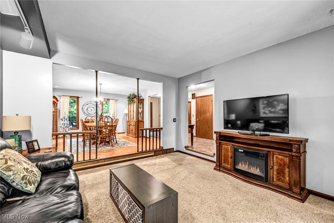 12938 Carter Road Painesville, OH 44077 - Photo 26 of 50 Living area with carpet floors, a glass covered fireplace, and a chandelier