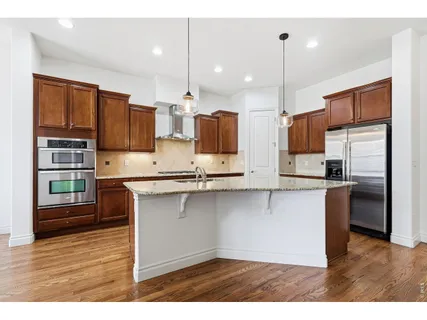 a open kitchen with stainless steel appliances granite countertop a refrigerator a sink a stove and a wooden floors