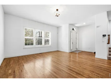 a view of an empty room with window and wooden floor