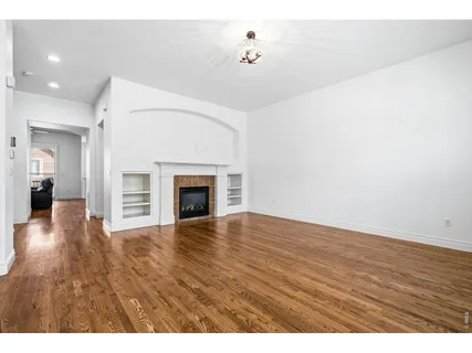 a view of empty room with wooden floor and fireplace