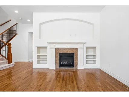 a view of an empty room with wooden floor fireplace and a window