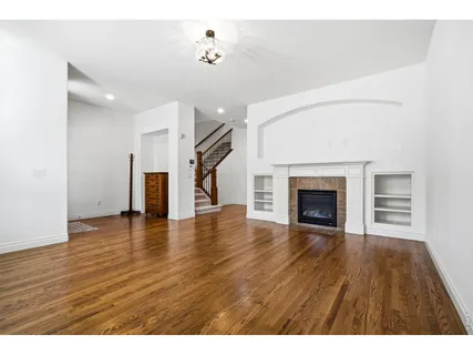 a view of empty room with wooden floor and fireplace