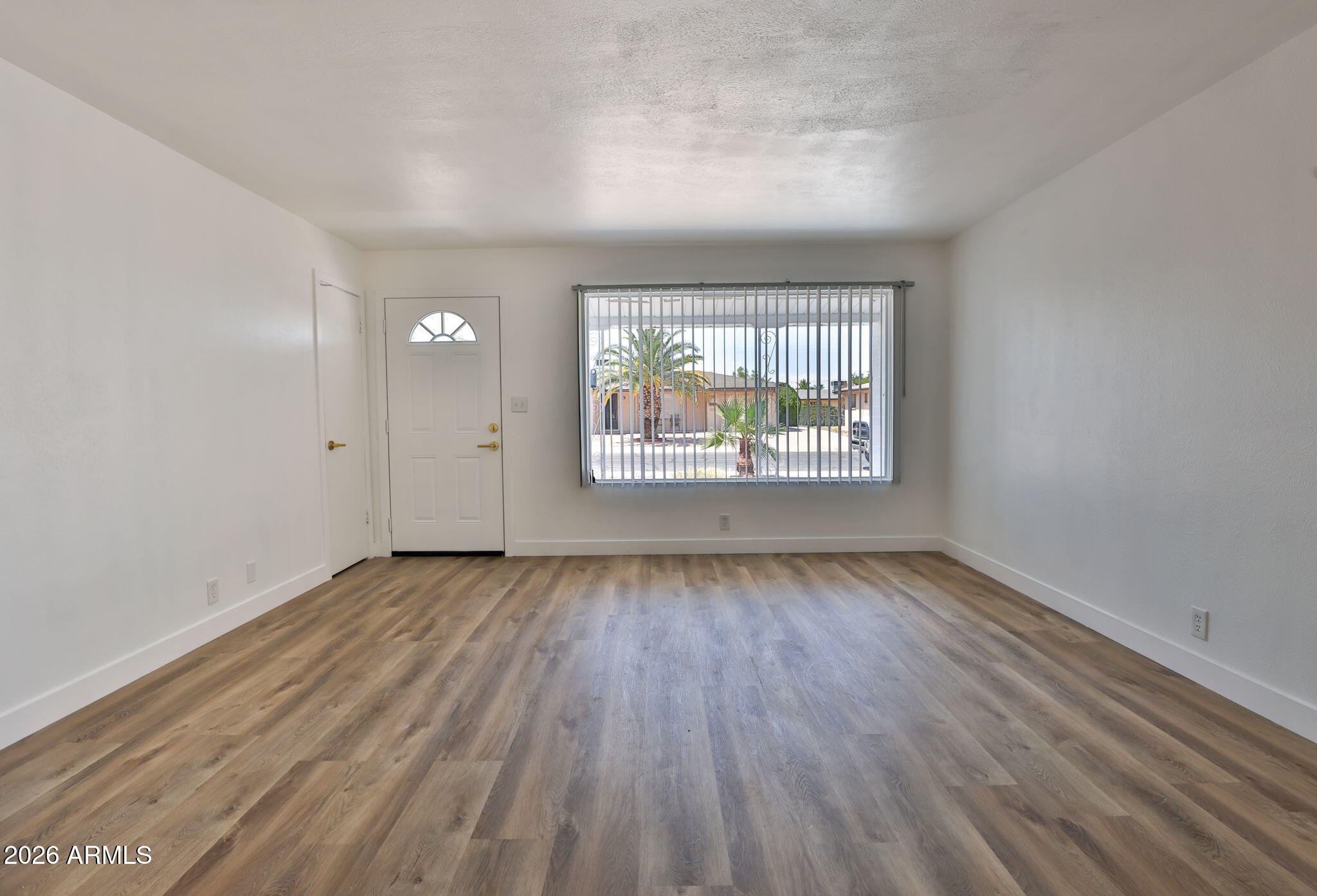 5510 East Dallas Street Mesa, AZ 85205 - Photo 5 of 24 an empty room with wooden floor and windows