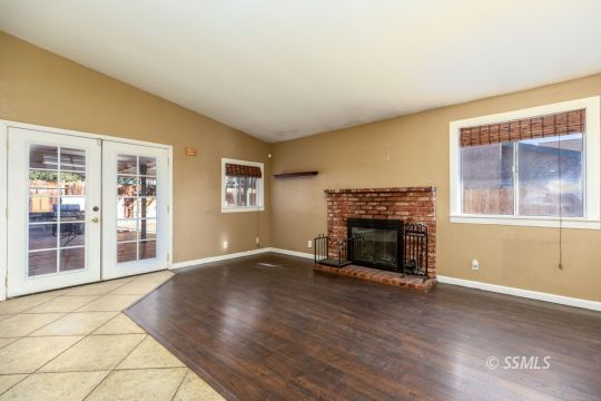 613 South Silver Ridge Street Ridgecrest, CA 93555 - Photo 15 of 26 an empty room with wooden floor fireplace and windows