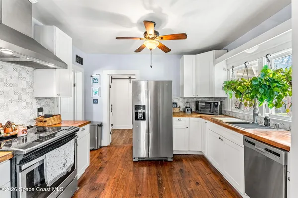 a kitchen that has a lot of cabinets a stove and a chandelier