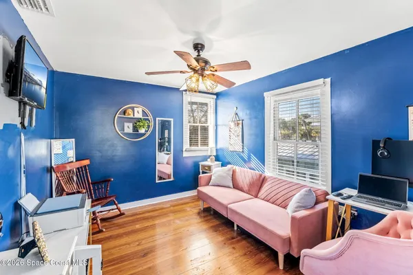 a view of a hallway to a livingroom with wooden floor and furniture