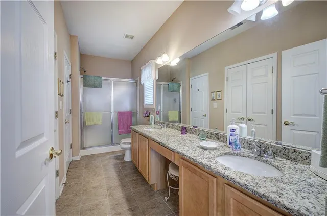 a bathroom with a granite countertop double vanity sink and mirror with shower