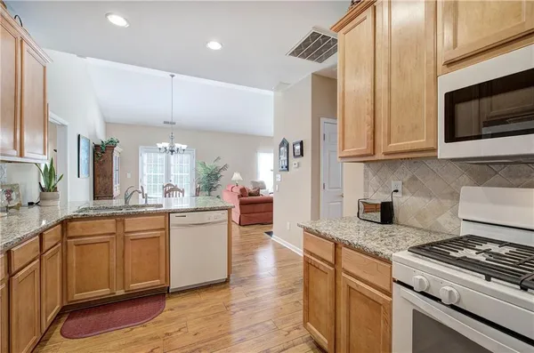 a kitchen with stainless steel appliances granite countertop a sink a stove and a wooden floors