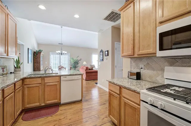 a kitchen with stainless steel appliances granite countertop a sink a stove and a wooden floors
