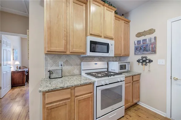 a kitchen with granite countertop a stove top oven microwave and refrigerator
