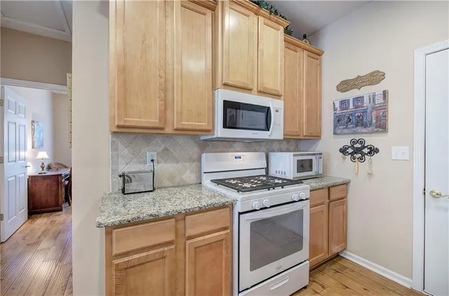 a kitchen with granite countertop a stove top oven microwave and refrigerator
