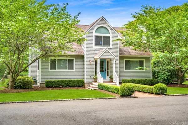 a front view of a house with a garden and trees