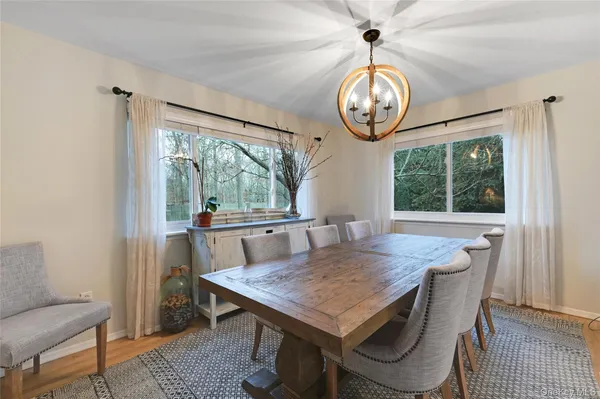 a dining room with wooden floor a chandelier a wooden table and chairs