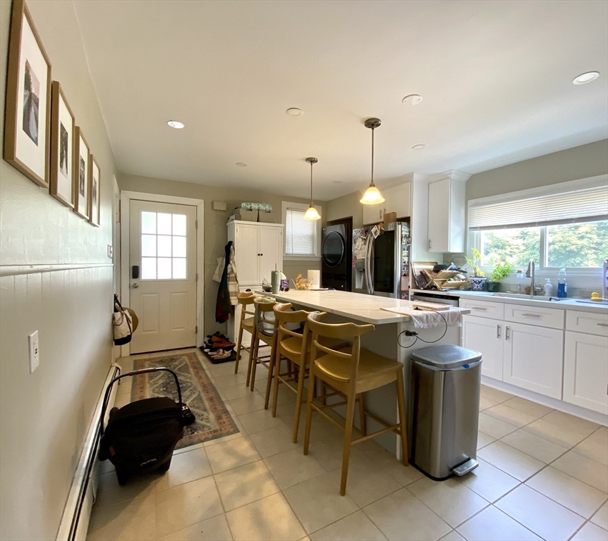 1011 Washington Street, Unit 1 Newton, MA 02460 - Photo 2 of 17 a kitchen with stainless steel appliances kitchen island granite countertop a table chairs and a refrigerator